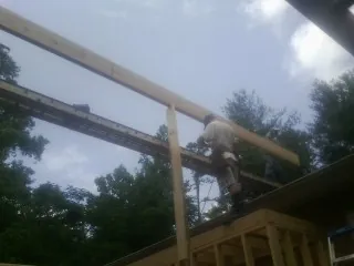 Carpenter setting a ridge beam over a new addition frame — Ice Dam Removal by Roofing Brothers in Charlo