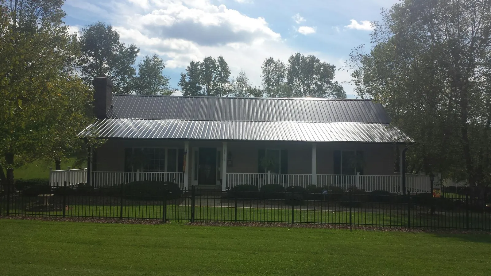 Gray metal roof on a brick ranch with a full width front porch — Gutter Guard Installation work by our crew in Charlo