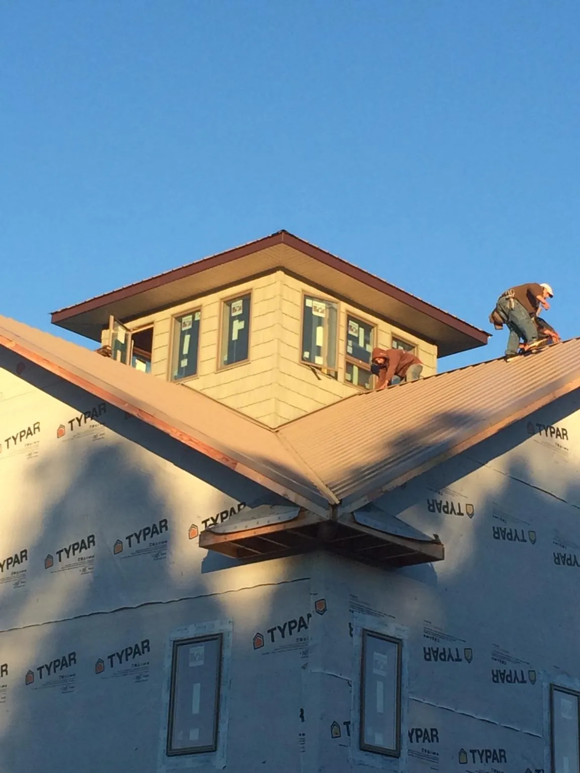 Roofers working around a rooftop cupola on a new metal roof at sunset — Roof Waterproofing in Charlo by Roofing Brothers